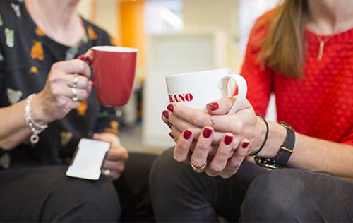 two co-workers sitting with cups of coffee