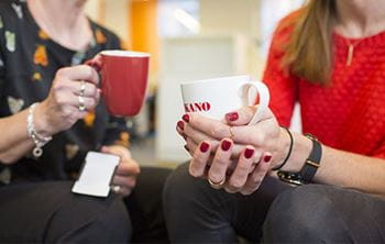 two co-workers sitting with cups of coffee