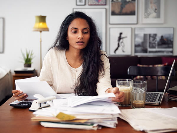 A woman looking at a pile of pare work and bills