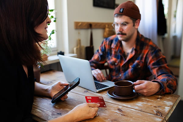 a couple using a credit card and laptop at the kitchen table